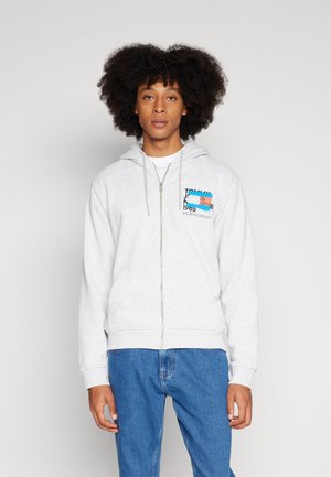 Sudadera gris con cremallera, bolsillo frontal, capucha con cordón, logo estampado en azul y naranja en el lado izquierdo del pecho, puños y dobladillo de canalé.