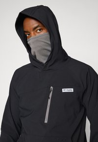 Black hooded jacket with a zippered chest pocket. Features a gray neck gaiter, textured fabric, and a prominent Columbia logo.