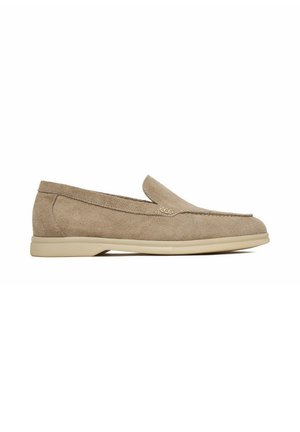 Mocasín beige de ante con suela de goma baja, costura tipo mocasín en la puntera y diseño minimalista, mostrado desde el lado exterior.