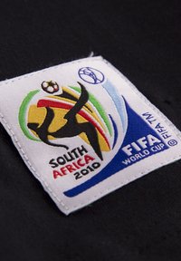 Geborduurd patch met het FIFA Wereldbekerlogo, in levendige kleuren: zwart, rood, geel, groen en blauw op een witte achtergrond. Inclusief de tekst "Zuid-Afrika 2010".