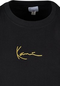 Black short-sleeve t-shirt with a round neckline featuring a gold embroidered logo. Smooth fabric texture, simple design, no additional patterns.