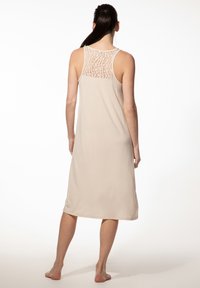 Beiges ärmelloses Kleid mit einem Spitzenrücken, knielangem Design, weichem Stoff und lockerem Schnitt. Schlichter und minimalistischer Stil.