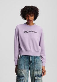 Lavender crew-neck sweatshirt made of cotton, featuring a black "KARL LAGERFELD JEANS" logo across the chest, with relaxed fit and ribbed cuffs.