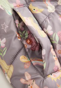 Gep quilteter Stoff in gedämpftem Lavendel mit einem verspielten Design, das Kaninchen, Blumen und Schmetterlinge zeigt. Sichtbares Detail mit Kupferdruckknopfverschluss.