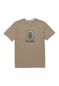 Camiseta de algodón beige con un diseño gráfico central que incluye el texto "Abraza lo Extraño" y acentos coloridos en azul y naranja.