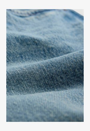 Țesătură din denim albastru deschis cu o suprafață texturată, având o țesătură clasică în diagonală și variații subtile de culoare și model.