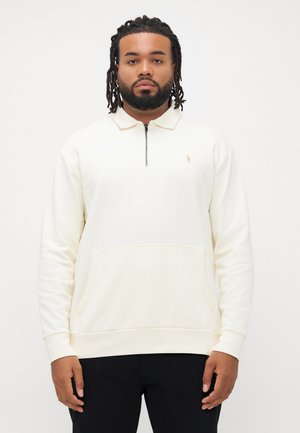 Sweatshirt med rund hals i krem med halv lynlås krave, ribbede manchetter og en frontlomme. Har et lille logo broderet på brystet.