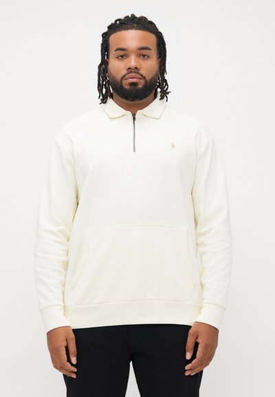 Beżowy sweatshirt z okrągłym dekoltem, z rozpinanym kołnierzem, prążkowanymi mankietami i kieszenią z przodu. Na piersi znajduje się małe haftowane logo.