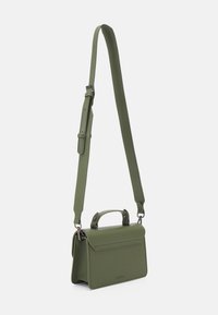 Zielona torba z wegańskiej skóry o strukturalnym kształcie, z górnym uchwytem, odpinanym paskiem na ramię i magnetycznym zapięciem. Na przodzie delikatne logo.