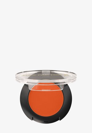 Blush crème Max Factor dans un boîtier rond, mat, orange avec un couvercle transparent et une base noire, présentant le nom de la marque sur le couvercle.