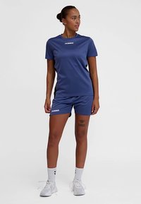 Granatowy komplet sportowy składający się z koszulki z krótkim rękawem i spodenek, wykonany z lekkiego materiału, z białymi akcentami logo i wygodnym krojem.