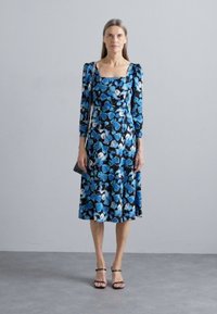 Φλοράλ φόρεμα με μπλε και λευκά σχέδια σε μαύρο φόντο, τετράγωνη λαιμόκοψη, μακριά φούσκες μανίκια και πλατύ στρίφωμα.