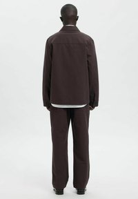 Pruun viimistletud jakk ja sobivad püksid siledas kangas. Komplekt on lõdva lõikega ning veidi tekstuurse viimistlusega.