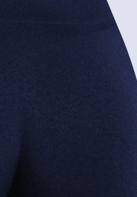 Marinblå leggings tillverkade av ett mjukt, elastiskt tyg, med en enfärgad och sömlös design i matt finish.