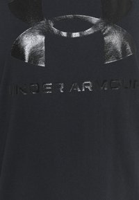 Juodame medvilninė marškinėliai su blizgiu juodu "Under Armour" logotipu ir tekstu. Audinys turi lygų paviršių be papildomų raštų.