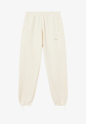 Helle Cremefarbene Sweatpants mit elastischem Bund, zwei Seitentaschen und elastischen Bündchen. Unauffällige Branding-Details in orange.