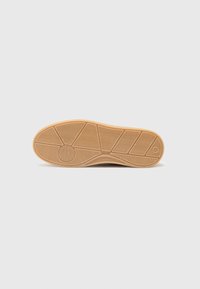 Suola di scarpa in gomma con un motivo testurizzato; presenta scanalature per una migliore aderenza; colore prevalentemente beige con una leggera lucentezza.