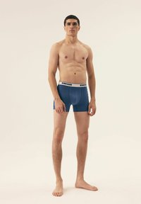 Męskie niebieskie bokserki z białą gumką z logo "Henderson". Gładki materiał, dopasowany krój i krótka długość nogawki.