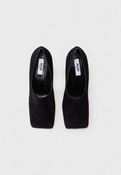 Pantofi cu toc pătrat din suede negru. Branțurile sunt netede, având un etichetă. Textura generală este moale.
