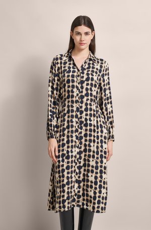 Bedrucktes Hemdkleid in Beige und Marineblau, mit einem Punktmuster, langen Ärmeln und einem lockeren Schnitt. Weicher Stoff mit glatter Textur.