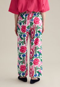 Pantalons large à motifs floraux colorés dans les tons de rose, rouge, vert et bleu, avec une taille élastique et un tissu léger pour un confort optimal.