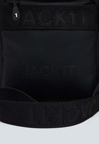 Sort nylon taske med en struktureret sort strop. Har et præget "JACK1T" logo på fronten og en lynlåslukning øverst. Kompakt og moderne design.