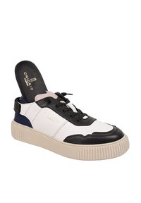 Sneakers en cuir blanc et noir avec une semelle beige texturée, des lacets noirs et une bande bleu marine. Logo présent sur la semelle intérieure.
