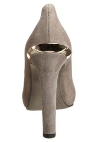 Beige suede high-heeled shoe with a pointed toe and a gold-accented cutout at the heel, featuring a sleek, smooth texture.