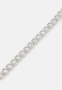 Sudraba tonis siksna ar aplīgo iestatījumu, kur skaidrie rhinestones sakārtoti nepārtrauktā līnijā, gluda metāla virsma un atstarojoši sīki acu daudzumi.