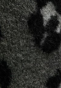 Tela texturada en negro y gris con una sensación suave, con un sutil patrón de print de leopardo en diferentes tonos.