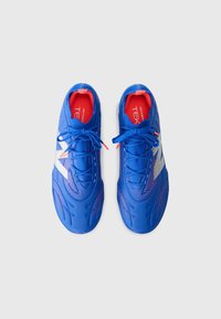 Sapatos desportivos azuis com um design elegante, apresentando um topo texturizado, detalhes em vermelho contrastante e um logótipo branco de lado.