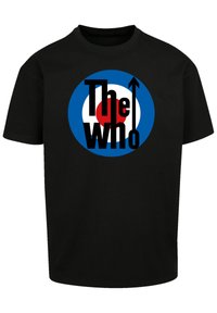 Schwarzes T-Shirt mit einem kreisförmigen blauen und weißen Grafikdesign mit rotem Zentrum und dem Text "The Who" in fetter schwarzer Schrift, mit einem nach oben zeigenden Pfeil.