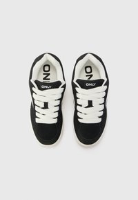 Black suede sneakers with white laces and branding, featuring a thick white sole and padded collar for comfort.