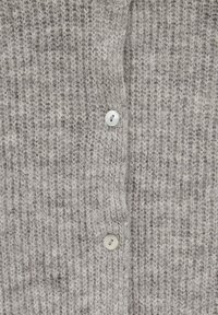 Audu adīkts džemperis gaiši pelēkā krāsā ar rakstainu struktūru. Iekļautas trīs baltas pogas un maiga, nedaudz pūkaina tekstūra.