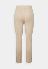 Leggings em bege com padrão canelado e um cós elástico, apresentando uma perna reta e bainha larga, feitos de um material de malha texturizada.