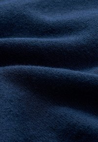 Granatowy materiał o miękkiej, teksturowanej powierzchni i drobny, wpleciony wzór, z delikatnymi fałdami i zagięciami w całej powierzchni.