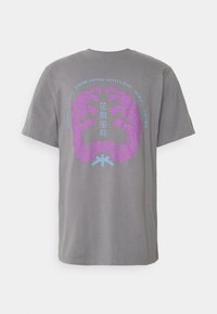 T-shirt en coton gris avec un design graphique violet et bleu au dos, comportant des motifs et du texte d'inspiration asiatique centrés dans un motif circulaire.