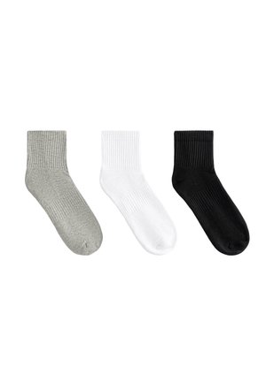 Trois chaussettes de crew à côtes en gris, blanc et noir, affichées côte à côte sur un fond blanc.