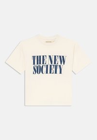 Camiseta de algodón color crema con mangas cortas y cuello redondo. Presenta un texto en negrita de color azul que dice "LA NUEVA SOCIEDAD" en la parte delantera.