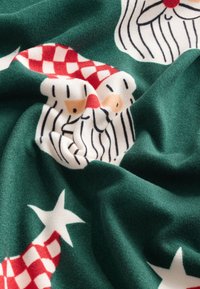 Zelená látka s motívom Santových tvárí, červenými károvanými klobúkmi a bielymi hviezdami. Mäkká textúra s živými, kontrastnými farbami.