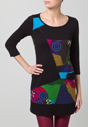 Musta tunika-mekko, jossa on monivärisiä kuvioita sinisen, vihreän ja violetin sävyissä. Kolme neljästä hihasta, pyöreä kaula-aukko ja nappi yksityiskohta sivuilla.