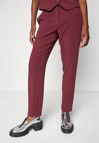 Vinosvarta byxor med rak bendesign, som har en mjuk textur och frontveck. Matchas med silvriga loafers och en matchande topp.