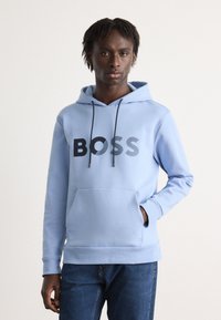 Világoskék kapucnis felső, puha anyagból, elülső zsebbel és fekete "BOSS" logóval. Felső zsinóros kapucnijával és bordázott szegélyével.