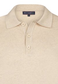 Polo beige con una texture morbida, tre bottoni e colletto piegato. Presenta un'etichetta cucita sul collo con informazioni del marchio e della taglia.