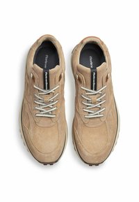 Beżowe zamszowe sneakersy z okrągłym noskiem, kontrastującymi białymi sznurówkami i grubą gumową podeszwą. Charakteryzują się minimalnym logotypem na języku.