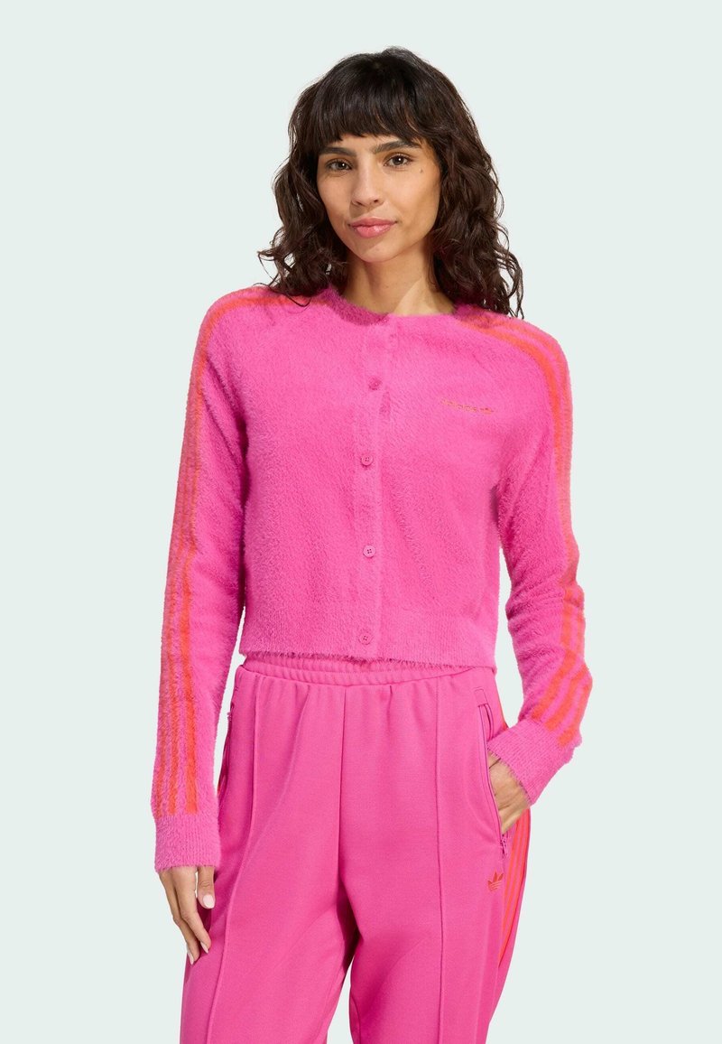 Bright pink cardigan featuring a fuzzy texture, round neck, and button closure. Striped orange accents run along the sleeves.
