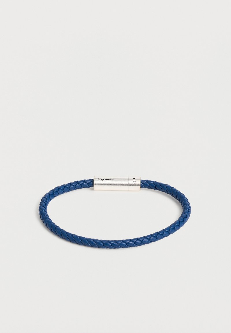 Bracelet en cuir tressé bleu avec un fermoir magnétique en argent gravé de "le gramme" et des marquages de poids.