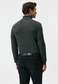 Ciemnoszary pulower z długim rękawem i wysokim kołnierzem, noszony z czarnymi dżinsami i czarnym paskiem, prezentujący gładką fakturę i dopasowany krój.