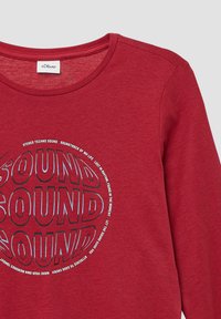 Rode lange mouwen shirt van zachte stof met een ronde grafiek met het woord "SOUND" in vette, gelaagd tekst en bedrukte ontwerpdetails.