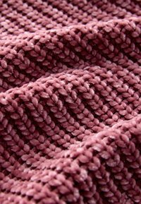 Weiches, strukturiertes Gewebe in einem gedämpften Mauve-Ton, mit dichten, plüschigen Schlaufen und einer plüschigen Oberfläche, die ein gemütliches, einladendes Erscheinungsbild schafft.